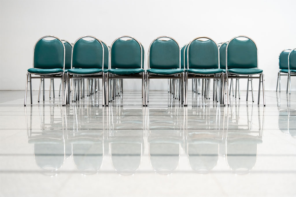 Row of green chairs arranged in a minimalist event space.