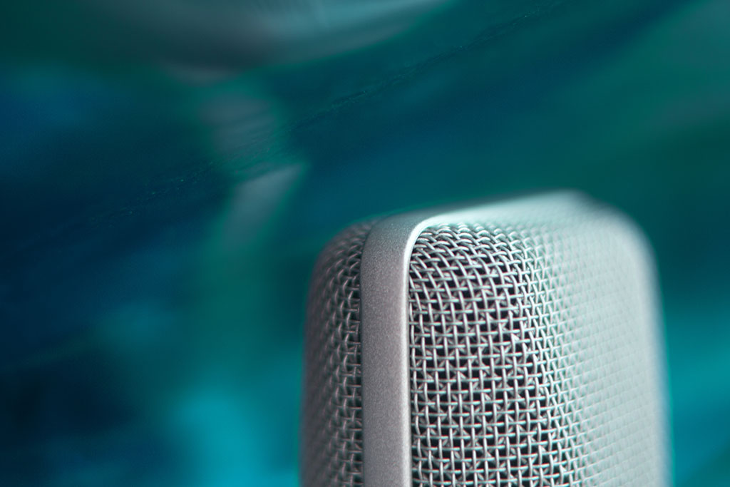 Close-up of a studio microphone against a green background.